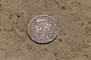 antique silver european coin on the sand