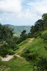 A dirt road among the jungle and mountains. Rural dirt road in the tropical forest in Thailand.