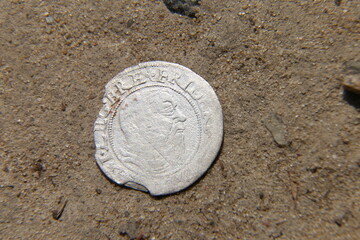 antique silver european coin on the sand