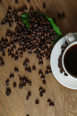 White coffee cup and coffee beans on wooden table with copyspace for text. Selective focus.