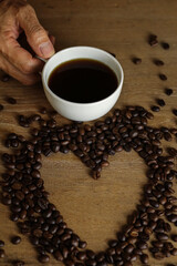 White coffee cup and coffee beans on wooden table with copyspace for text. Selective focus.