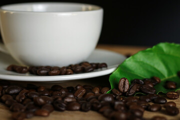 White coffee cup and coffee beans on wooden table with copyspace for text. Selective focus.