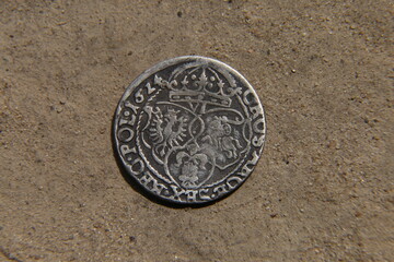 antique silver european coin on the sand
