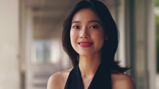 Close up of one young beautiful Chinese woman looking at camera smile attractive elegant Asian lady in black dress portrait 4k slow motion