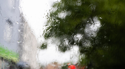 Blurred raindrops on a windscreen glass with a night city lights at the background.