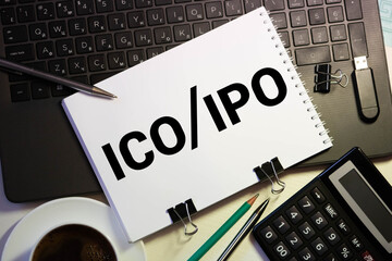 A Notebook with Business notes initial coin offering ICO vs IPO Initial Public Offering with office...