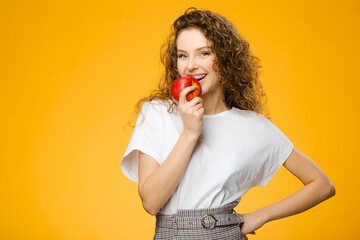 Pretty girl with curly hair holding fresh apple