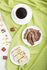 traditional arabic sweets sesame halva with chocolate and pistachio and a cup of coffee on a white wooden background. top view, close up.