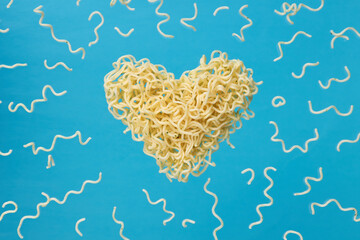 instant noodles advertisement photo. levitated noodle heart symbol over blue trendy background. outer space. for design and ornate. love fast food concept.