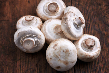 stack of raw fresh champignon mushrooms close up on a wooden rustic background.