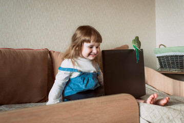 happy girl at home. home pet. budgerigar. laptop and gadgets. Baby watching cartoons, or online games.