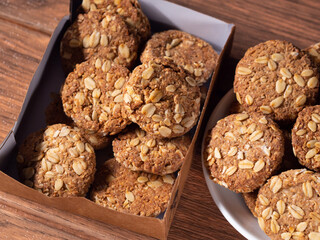 many oatmeal cookies in a cardboard box and on a plate close-up