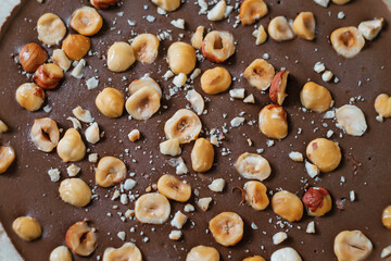 Homemade chocolate cake with nuts on parchment paper. Food delivery. Homemade baking. Top view close-up. Delicious tart with chocolate and nuts on the wooden table.