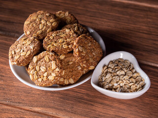 many fresh oatmeal cookies on a plate and fresh oats on the right close-up