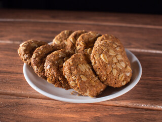 many sweet oatmeal cookies on a white plate on a wooden board