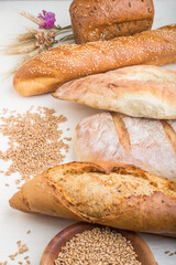 Different kinds of fresh baked bread on a white wooden background. side view.
