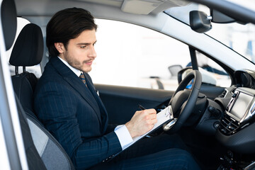 Obraz premium Car Seller Sitting In Auto Taking Notes In Dealership