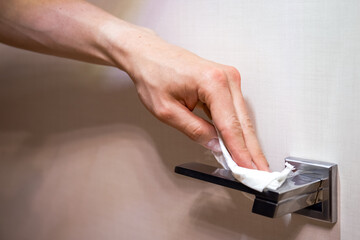 Coronavirus COVID-19 Prevention cleaning man wiping doorknob with antibacterial disinfecting