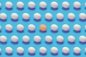 Single colored egg among white eggs solid color background