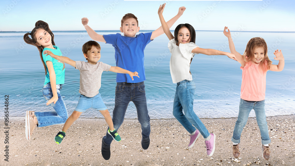 Wall mural Group of school children jumping on beach near sea. Summer holidays