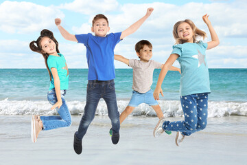 Group of school children jumping on beach near sea. Summer holidays