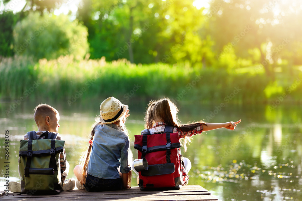 Poster school holidays. group of children sitting on wooden pier near river