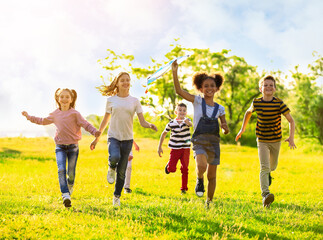 School holidays. Group of happy children playing with kite outdoors
