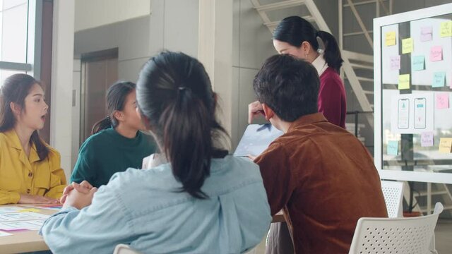 Group of Asia young creative people meeting brainstorming ideas conducting business presentation ideas mobile application software design project colleagues in modern office. Coworker teamwork concept