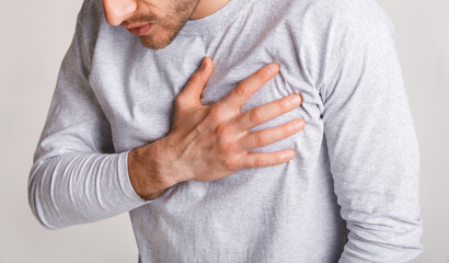 Stress and health concept. Young man experiences chest pain and leans