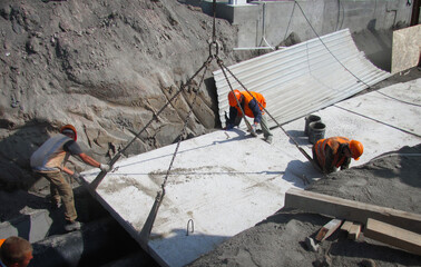 builders work on the construction site and pipes, lay concrete foundation slabs, prepare the ground, compact the ground - obrazy, fototapety, plakaty
