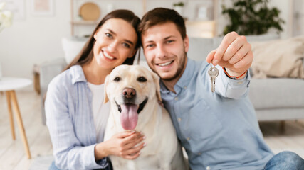 Young happy couple with dog showing keys