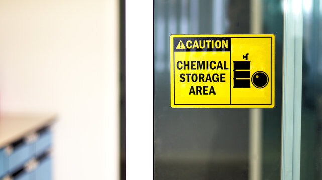 Black-yellow Chemical storage area Hazard Sign and symbol on the glass door, Caution for warning dangerous space in laboratory room. selective focus on tag, blurred background Safety first concept.