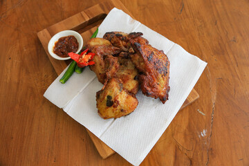 Photo of fried chicken food served with hot chili sauce and decorated with tomatoes and green chili