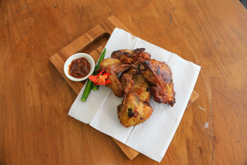 Photo of fried chicken food served with hot chili sauce and decorated with tomatoes and green chili