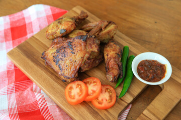 Photo of fried chicken food served with hot chili sauce and decorated with tomatoes and green chili