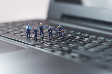 Miniature police squad protecting laptop computer. Technology concept