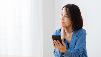 Naklejka premium スマートフォンを使う中年女性