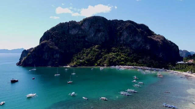 High aerial tilt-up over harbour and turquoise waters of Corong Corong Beach, El Nido, Palawan, Philippines