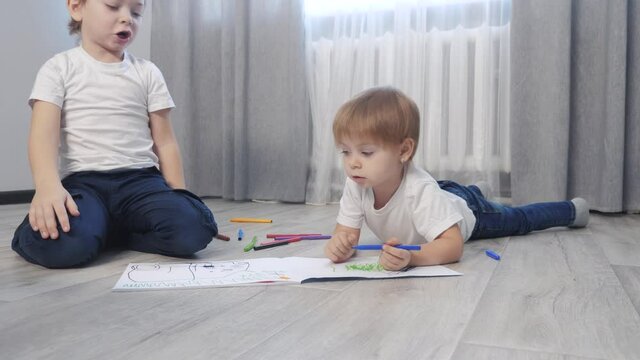 children draw with felt-tip pens in an album. little lifestyle boy and girl concept childhood brother and sister play paint on the floor with colored markers