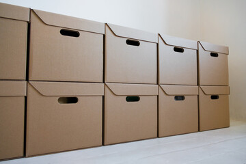 Cardboard boxes for storage that are neatly stacked against a white wall. Concept of delivery.