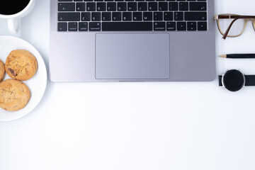 White office desk table with laptop computer, pen, smartwatch, Cookies, green plant, cup of black coffee and supplies. Top view with copy space, flat lay. - Powered by Adobe