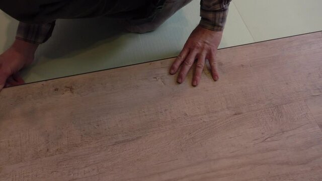 A worker puts a new laminate on the floor. Laying the floor covering. Master in the house.