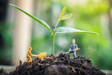 Miniature people team works to inspect and plant trees for a green world project. (We plant trees for a better world)