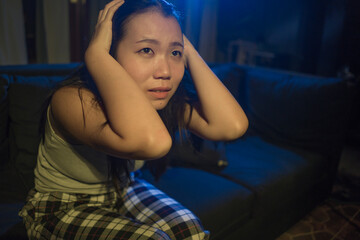 Obraz premium young beautiful sad and depressed Asian Korean woman crying in tears on darkness in pain feeling worried and helpless sobbing desperate at living room sofa couch