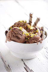 Chocolate ice cream balls with pistachio and cookies in a white bowl