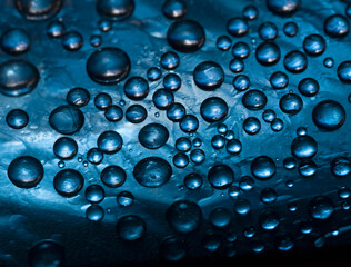 Abstract deep blue background of drops and droplets. Close up. Illuminated by the bright sun blue drops of water are falling down.