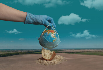 The concept of the agricultural crisis during the virus and quarantine. In the photo, the hand holds a globe in a medical mask. Against the background of an empty wheat field