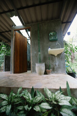 The bathroom is made of bare cement and decorated with trees.
