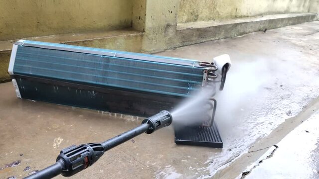 AC Mechanic Cleaning Split AC Copper Indoor cooling coil with using water . Air Conditioner Cleaning Indoor Unit Using Water gun. Man cleaning air conditioner unit by water. maintenance service.