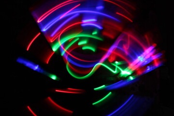 blurred of Green, red and purple light painting photography, long exposure, ripples and waves against a black background